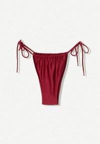 Piros bikini alsó állítható pántokkal, rugalmasságot biztosító anyagból készült. Összegyűrt oldalai vannak a kényelmes illeszkedés és a minimális takarás érdekében.