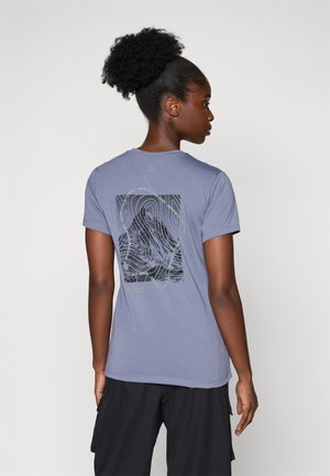 Camiseta de manga corta, ligera, de color azul-gris con un diseño gráfico negro y texto verde en la parte posterior, sobre un fondo liso.