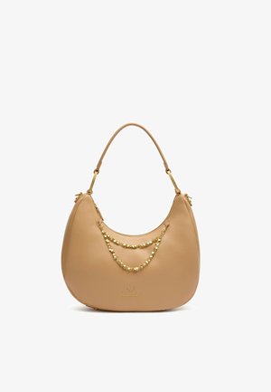 Beige leren handtas met gebogen vorm, enkele schouderriem en twee decoratieve gouden kettingen aan de voorkant met het merklogo.