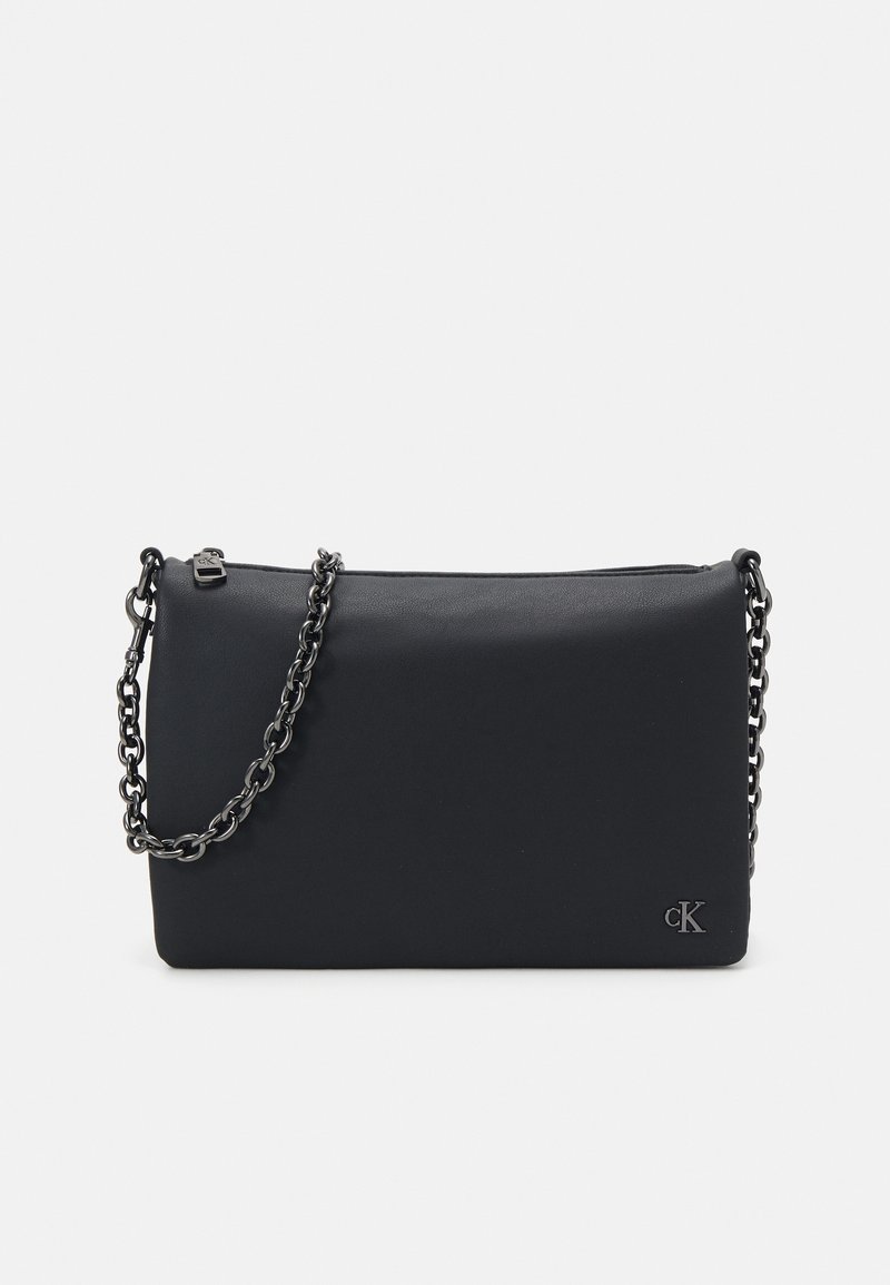Czarna, prostokątna kopertówka wykonana z gładkiego materiału, z łańcuszkiem na ramię i małym logo z boku, zapinana na zamek.