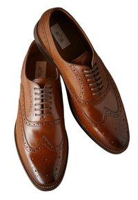 Chaussures de ville en cuir marron avec des détails en brogue, un bout rond et six œillets pour les lacets. Finition lisse avec une teinte beige.