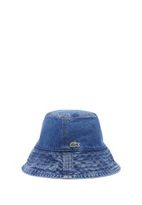 Gorra de cubo de denim en azul con un acabado texturizado y costuras en contraste. Presenta un pequeño logo verde de Lacoste en el lateral.
