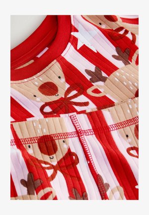 Czerwony top z prążkowanej tkaniny z wzorami reniferów i gwiazd w kolorze brązowym i białym. Okrągły dekolt z czerwoną lamówką i szczegółami w kontrastowym ściegu.