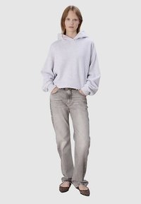 Sweat à capuche court gris clair avec cordon de serrage, accompagné d'un jean gris délavé à jambes droites et de ballerines noires à imprimé léopard.