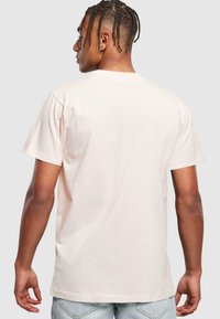 Lyserød kortærmet t-shirt lavet af bomuld, med rund hals og en afslappet pasform. Stofoverfladen er glat med en let glans.