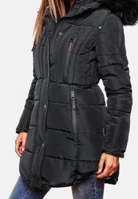 Svart vinterjacka med huva, vadderad design, horisontell quiltning, flera dragkedjefickor och imitationspäls på huvan. Slät textur.