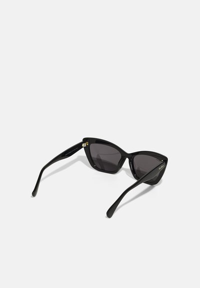 Lunettes de soleil cat-eye noires avec une finition brillante, verres teintés foncés et accents en doré sur les branches. Design élégant et extrémités effilées.