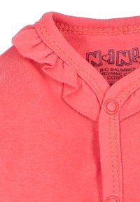 Coral-colored cotton top with a ruffled neckline, featuring a button closure and printed label inside. Soft, smooth texture.