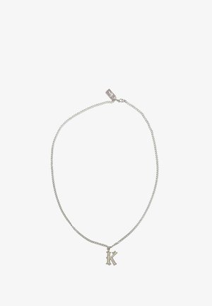 Stříbrný řetízek s přívěskem ve tvaru výtvarného velkého „K“, zdobeným drobnými čirými kamínky podél písmene.