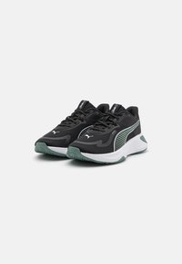 Baskets de sport noires avec une tige en mesh texturé, ornées d'accents blancs et verts, d'une semelle rembourrée et d'un design épuré.