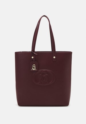Bordeauxfarbene Tragetasche aus glattem Material, mit einem eingeprägten Logo, zwei Griffen, einem Anhänger mit Metallbeschlägen und einer schlanken, rechteckigen Form.