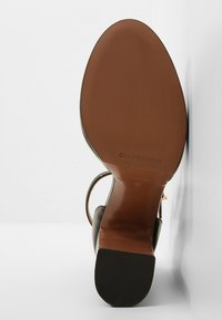 Sandale à talon pour femme avec semelle marron vue de la semelle montrant la marque "L'AUTRECHOSE" et la taille 37.