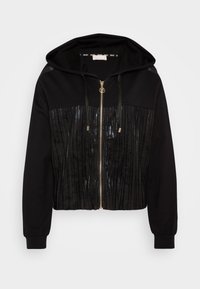 Felpa nera corta con zip frontale, tessuto plissettato lucido sul torso, maniche lunghe morbide e dettagli con coulisse sul cappuccio.