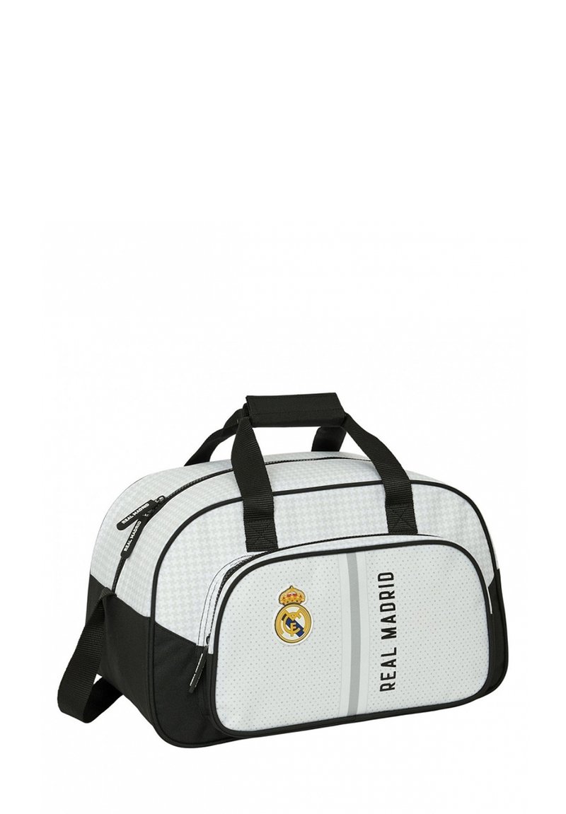 Torba sportowa w białym i czarnym kolorze, z teksturowanym wzorem, górnymi uchwytami, przednią kieszenią na zamek błyskawiczny oraz logo Real Madryt.