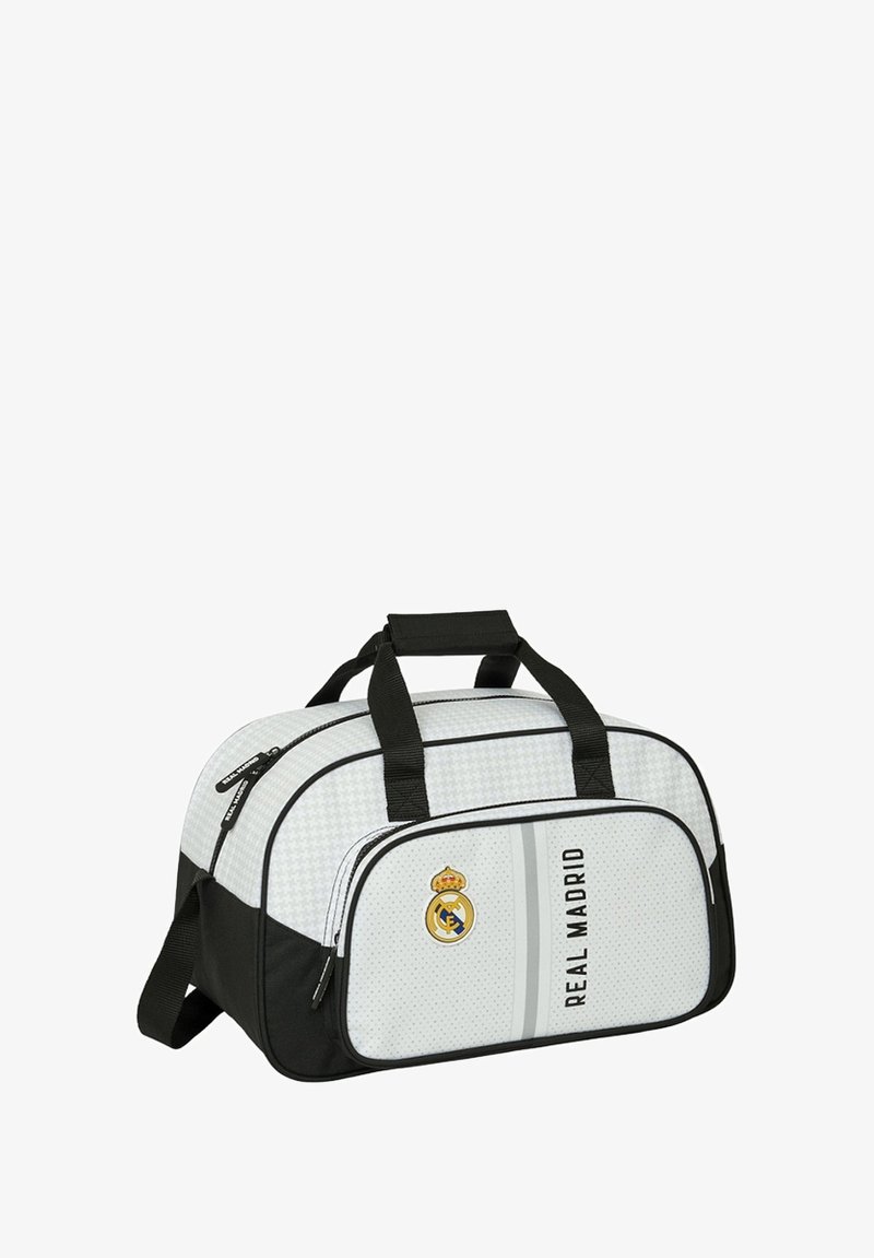 Torba sportowa w białym i czarnym kolorze, z teksturowanym wzorem, górnymi uchwytami, przednią kieszenią na zamek błyskawiczny oraz logo Real Madryt.