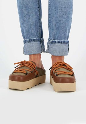 Scarpe con zeppa con tomaia in pelle marrone e tela beige. Presentano lacci arancioni, occhielli neri e una suola texturizzata e chunky.