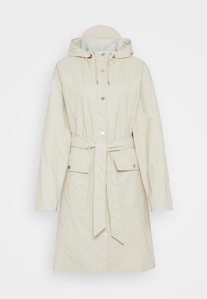 Cappotto impermeabile beige con cappuccio, maniche lunghe e vita con coulisse. Presenta bottoni a pressione e due grandi tasche frontali. Tessuto liscio.