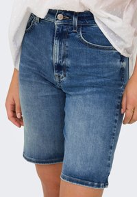 Gaiši zili džinsu šorti ar brīvu piegriezumu. Iekļauj pogas aizdari, piecas kabatas un apgrieztu malu.