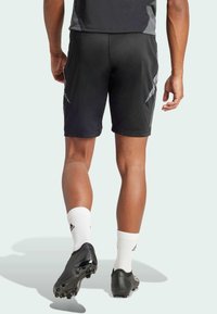 Schwarze Sportshorts mit einer engen Passform, ausgestattet mit grauen Akzenten und einem leichten, strukturierten Stoff. Kombiniert mit schwarzen Fußballschuhen und weißen Socken.