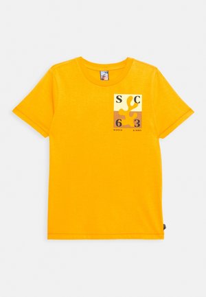 Camiseta amarilla brillante de manga corta con cuello redondo y un pequeño estampado en el pecho que muestra formas abstractas, los números 6 y 3, y el texto "Scotch & Soda."