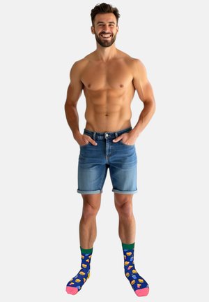 Denim shorts med opsmøgede kanter, lys blå farve. Farverige, mønstrede sokker med madvarer på en blå baggrund med pink og grønne accenter.