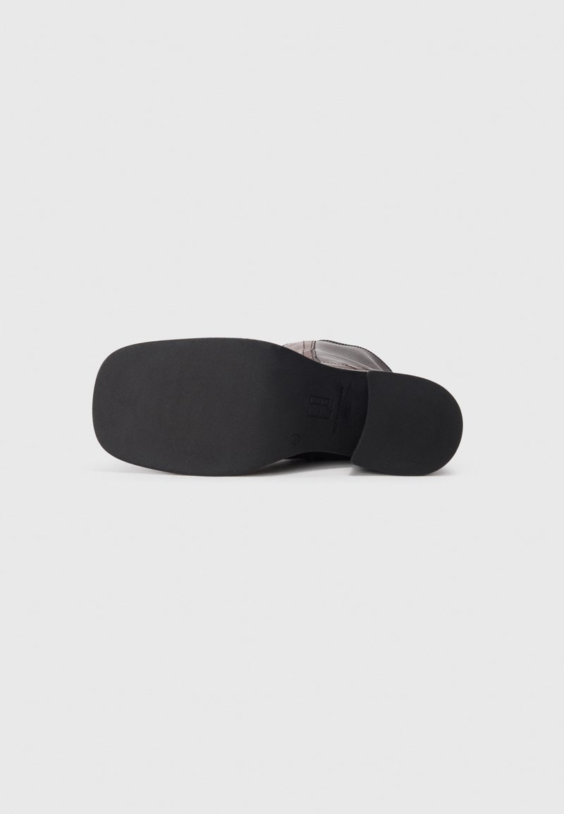 Chaussures noires avec une semelle en caoutchouc lisse, présentant un dessus gris texturé et des éléments de design minimalistes. Style plat sans matériel visible.