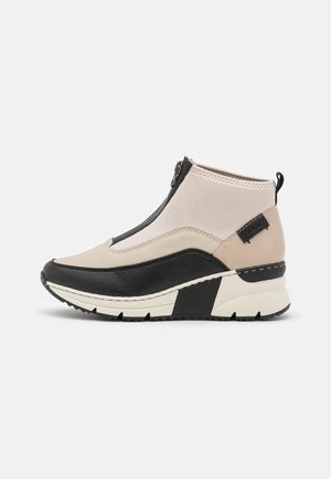 Black and beige ankle boots with a zip closure, synthetic upper, textured black panel, and a thick, ridged, white outsole.