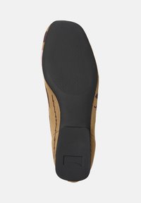 Sole of a shoe featuring a textured black rubber bottom with a brown patterned upper and a distinctive heel shape.