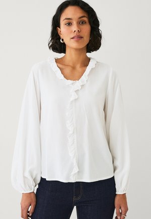 White blouse with a ruffled neckline and long puffed sleeves. Made of lightweight fabric, featuring a relaxed fit and simple button detail.