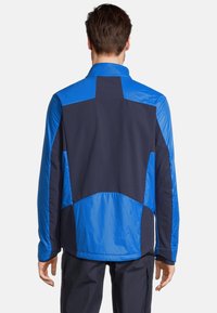 Veste pour homme présentant un mélange de couleurs marine et bleu vif, fabriquée en tissu léger et lisse avec des motifs de panneaux contrastants.