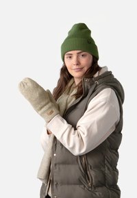 Moufles en tricot beige avec un motif texturé, bonnet vert clair, gilet matelassé gris sur un sweat crème, et écharpe claire.