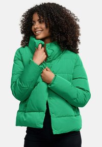 Giacca puffa verde con colletto alto, caratterizzata da un design trapuntato e bottoni a pressione, realizzata in un materiale leggero e lucido.