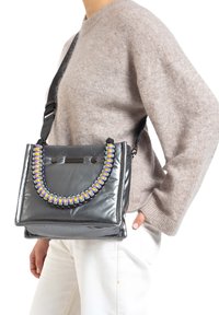 Sac à main en cuir verni gris avec une anse tressée multicolore épaisse et une forme rectangulaire épurée. Comprend une bandoulière réglable.