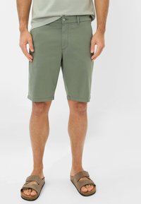 Khaki shorts lavet af letvægtsstof, med knap- og lynlåslukning, sidelommer og opkrøllede kanter. Bæres med brune slip-on sandaler.