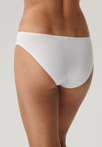Białe bawełniane majtki bikini o gładkiej fakturze, niskim kroju i minimalnym szwie, prezentujące prosty i klasyczny design.