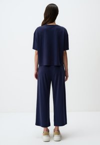 Set di abbigliamento da casa in blu navy, composto da un top corto con maniche ampie e pantaloni dal fit morbido, realizzato in un tessuto soffice e dalla texture liscia.