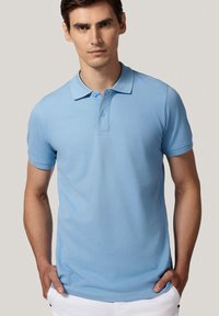 Jasnoniebieska koszulka polo wykonana z bawełny, z klasycznym kołnierzykiem, krótkimi rękawami i zapięciem na dwa guziki. Gładka faktura i dopasowany krój.