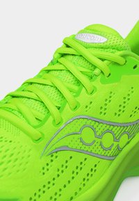 Φωτεινό πράσινο παπούτσι τρεξίματος Saucony με διαπνέον δίχτυ, κορδόνια και ανακλαστικό λογότυπο στο πλάι.