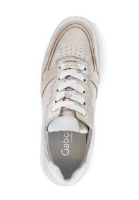 Beige leren sneaker met witte veters en afwerkingen, met geperforeerde details en een gouden accent op de vetertjes. Zachte textuur, lichtgewicht ontwerp.