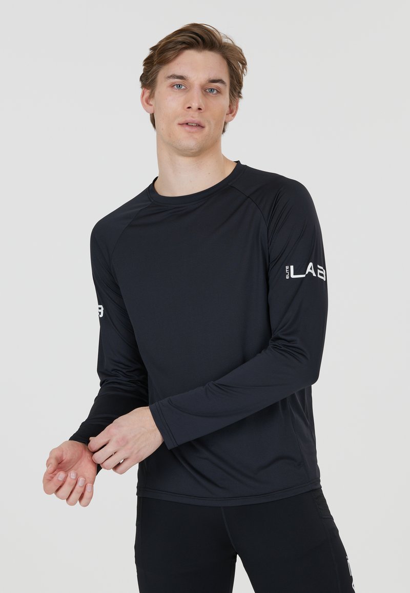 Zwart langemouwen sportshirt gemaakt van een lichte stof, met een ronde halslijn en een logo op de linkermouw.