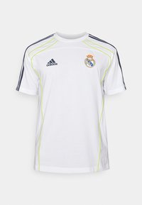Camiseta blanca de adidas de manga corta, con detalles en azul marino y ribete verde limón. Incluye el logotipo bordado del Real Madrid en el pecho.