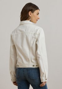 Balta denim jaka ar klasisku apkakli, pogām uz piedurknēm un sānu pogām, kombinēta ar ziliem denim džinsiem.