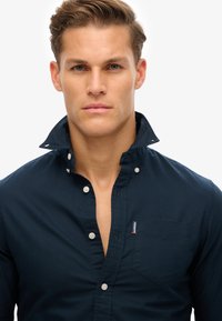 Navy blauwe button-up shirt met een kraag halslijn, een borstzak en een subtiele logo-tag, gemaakt van een gladde katoenstof en een klassiek ontwerp.