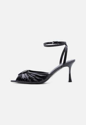 Sandale à talon haut en cuir verni noir avec bout ouvert, devant froncé et bride de cheville réglable avec boucle.