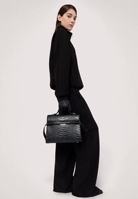 Černá kabelka z kůže s krokodýlím reliéfem, s plochým horním držadlem, elegantním designem a jemnými kovovými detaily. Elegantně kombinovaná s černým oblečením.