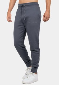 Grijze sweatpants met elastische tailleband en trekkoord. Aansluitende benen met ribgebreide manchetten. Voorzien van geborduurd logo detail op de dij.