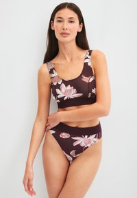 Bordeaux twee-delige bikini met bloemmotieven in roze en wit. De top heeft brede bandjes, terwijl de onderkant hoog opgesneden is.