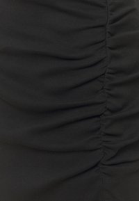 Svart rynkad tyg med horisontella veck, med en mjuk, elastisk textur. Inga synliga mönster eller hårdvarudetaljer.