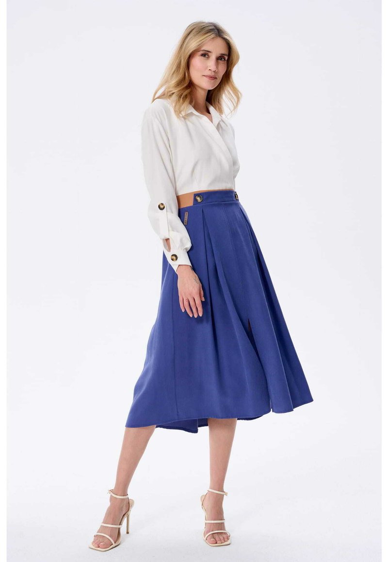 Biała bluzka z długim rękawem i zapięciem na guziki, zestawiona z niebieską plisowaną spódnicą midi z przednim rozcięciem i złotymi guzikami jako akcentami.