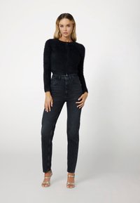 Black fuzzy cropped sweater with long sleeves, paired with high-waisted black jeans and silver strappy heels. Smooth textures and fitted design.
